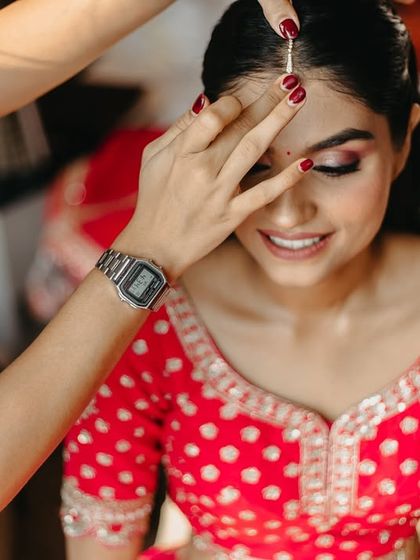 The final touches of makeup, a small bindi being placed on the bride's forehead. We capture the details that complete the bridal look.