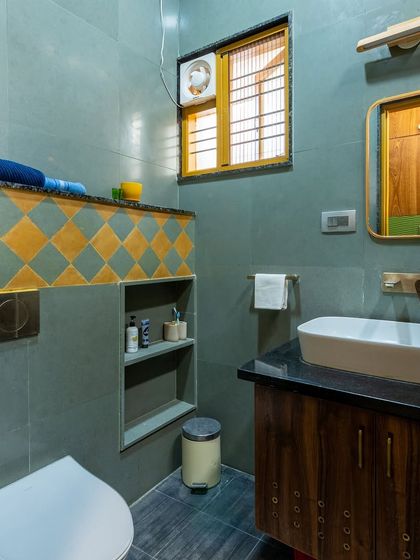 The bathroom vanity area, with a vessel sink on a black granite counter, a custom wood cabinet, and a matching wood-framed mirror.