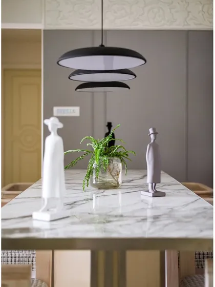 The dining table is a piece of art in itself, with its smooth marble top and modern decor. The suspended lights add a touch of drama and sophistication.