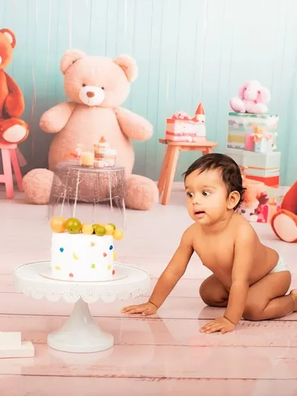 A baby curiously reaching for the cake during a first birthday photoshoot. These are the moments that tell a story.