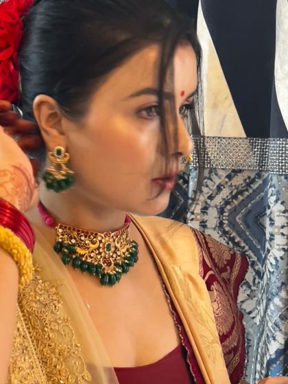 A beautiful profile shot of my client getting ready. Her hair is adorned with flowers, perfectly complementing the traditional aesthetic of the green and gold jewellery set she is wearing.