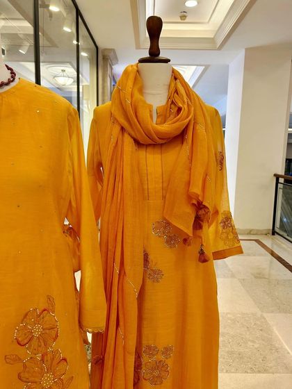 A closer look at a sunshine yellow kurta set, styled with a matching dupatta wrapped around the neck for an elegant, complete look.