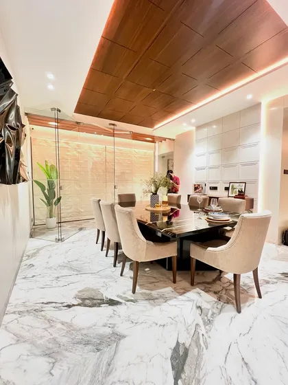 In this dining room, we created a sense of drama and elegance. The design features a stunning wooden ceiling detail that draws the eye, casting a warm glow over the custom black marble dining table and plush, neutral-toned chairs.