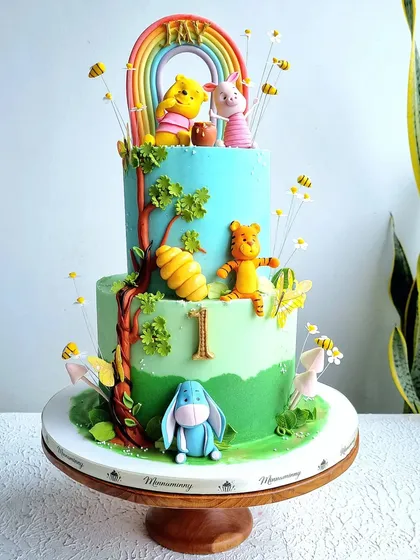 A full view of the two-tiered Winnie the Pooh cake on its stand.