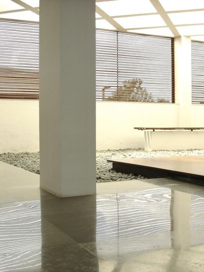 An interior zen garden with polished floors and slatted blinds at the Zanav Home Studio. This space was designed as a quiet, contemplative corner within the larger studio, bringing natural elements indoors to create a peaceful atmosphere.