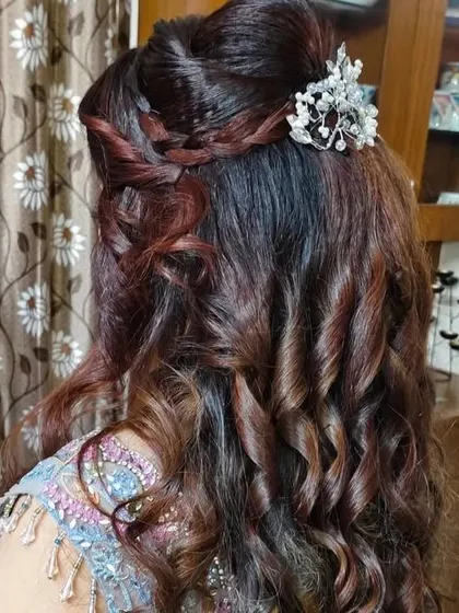 A party-ready hairstyle with soft curls and a delicate, sparkling hairpiece.