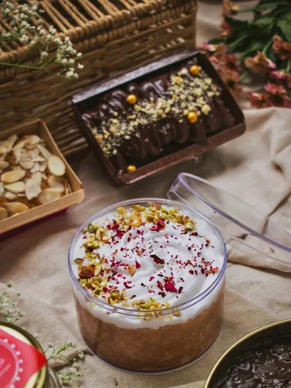 A collection of desserts from a home baker, including a tres leches tub cake and chocolate loaf cakes. The styling with a picnic basket and cloth gives it a rustic, homemade feel.