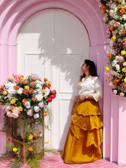 A pensive moment against a beautiful pastel pink door and floral decor. Even in quiet moments, the host's presence is felt.