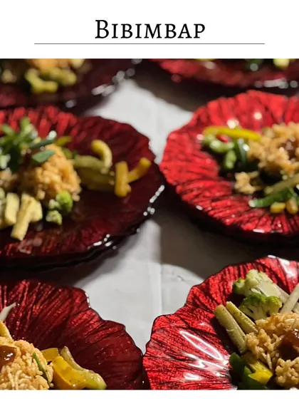 My version of a vegetarian Bibimbap, served on a striking red glass plate. This Korean-inspired dish is a vibrant mix of seasoned rice, fresh vegetables, and a savory sauce.