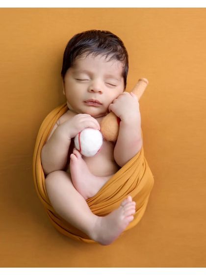 A variation of the baseball theme, showing the baby holding both the ball and bat. We have a variety of small props to customize your session.