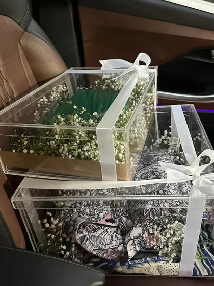 Your bridal trousseau deserves a special welcome. We design exquisite trousseau packaging, like these elegant clear acrylic boxes filled with baby's breath, to make unboxing your precious outfits a memorable moment.
