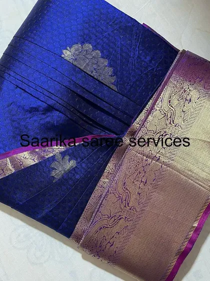 A royal blue saree with a purple and silver border.