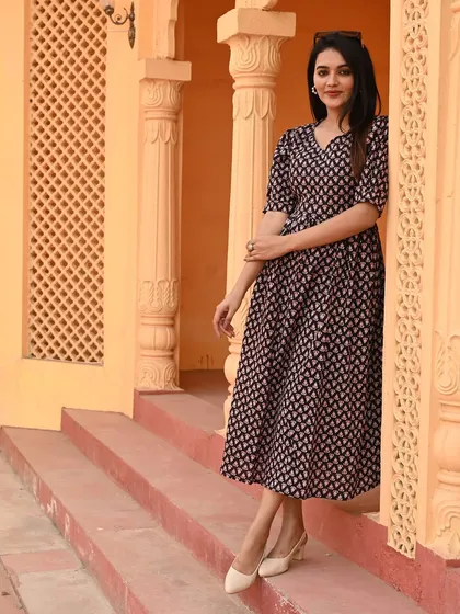 A full-length shot of the puff-sleeve dress in a classic black and white print, styled elegantly against a traditional backdrop.