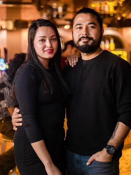 A couple posing for a photo at the bar.