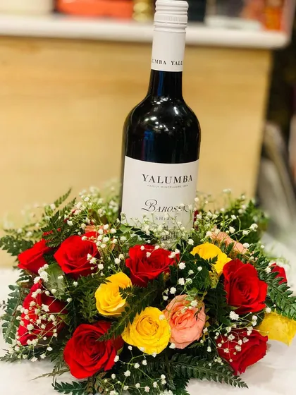 A slightly different angle of the wine and flower centerpiece, showing the lushness of the surrounding roses and ferns.