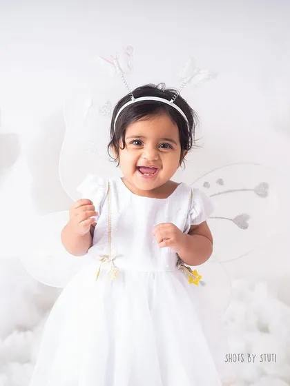 A happy smile amidst the clouds. The all white, dreamy setup is perfect for creating angelic and timeless first birthday portraits.