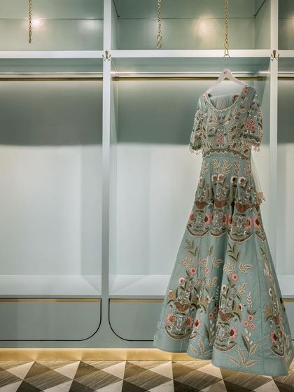 The display systems in the fashion studio are designed to be minimal yet elegant. A single garment is highlighted against a serene, mint-green backdrop with integrated lighting, turning the clothing itself into a work of art.