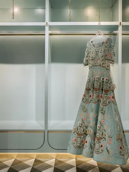 The display systems in the fashion studio are designed to be minimal yet elegant. A single garment is highlighted against a serene, mint-green backdrop with integrated lighting, turning the clothing itself into a work of art.
