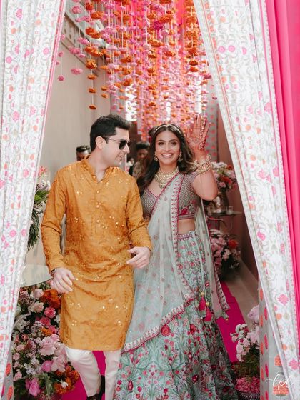 Making a grand entrance. The bride waves happily as she enters her Mehendi ceremony. Her makeup is bright and radiant, ensuring she stands out amidst the colorful and festive atmosphere.