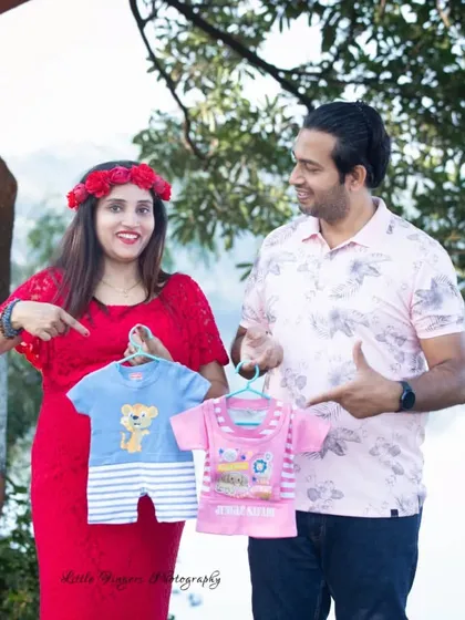A fun and colorful gender reveal moment. This couple playfully points to blue and pink baby clothes, sharing their excitement for what's to come.