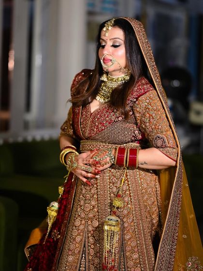 A graceful three-quarter portrait of the bride, highlighting her stunning jewelry and the rich embroidery of her lehenga.