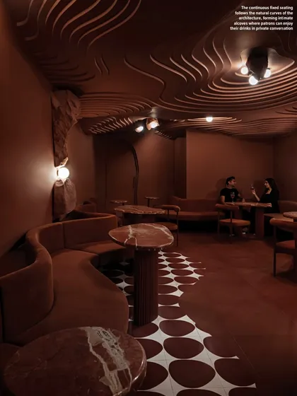For the "Whispers in Motion" speakeasy, we created an intimate, cave-like atmosphere. The design blends the raw spirit of a cave with the calm of a Japanese zen garden, using continuous seating and a fluid, layered ceiling to invite guests into a world of mystery.