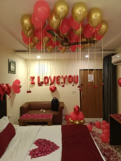 This angle of the "I love you" decor shows the foil balloon banner on the wall and the rose petals spread across the sofa, ensuring every corner of the room feels romantic.
