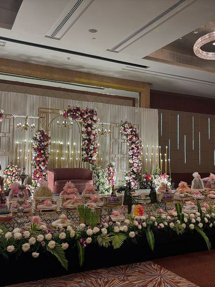 A wider view of the geometric floral arch stage, showing the full length of the offering table.