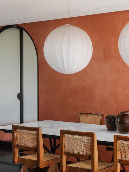 A closer view of the custom marble-topped dining table. The contrast between the smooth, cool marble and the warm, caned chairs is a deliberate choice to create a rich, tactile experience.
