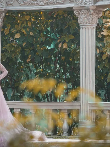 The bride-to-be looks absolutely radiant in her pink gown, framed by the elegant pillars of this garden gazebo studio set.