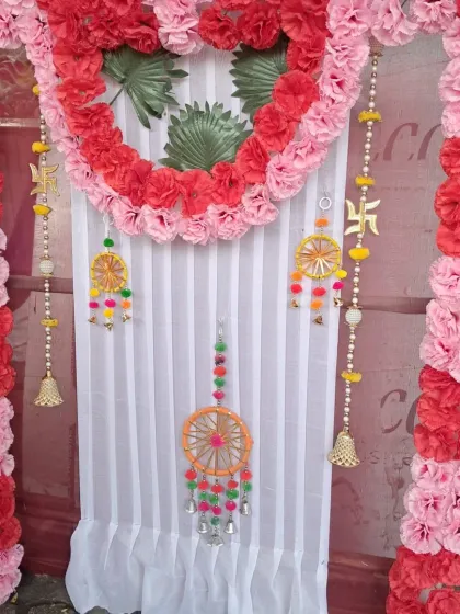 This backdrop for Ganesh Chaturthi shows how I can incorporate specific spiritual symbols into the design. It features a heart-shaped floral arrangement and hanging Swastik symbols, framed by red and pink artificial carnations.
