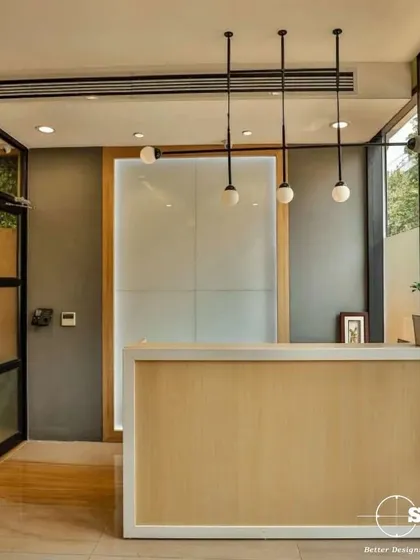 The first impression matters. Here is a reception area we designed with a minimalist wooden desk, elegant globe pendant lights, and large glass panels that invite natural light, creating a welcoming and professional entry point for clients and staff.