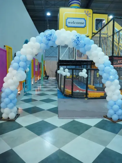 A simple and elegant blue and white balloon arch provides a beautiful entrance to the play area for a birthday party.