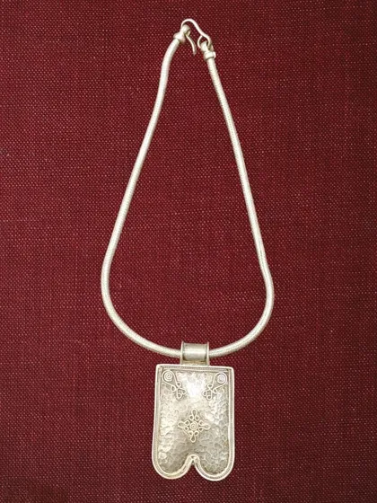 A simple yet striking oxidised silver pendant on a classic snake chain. The pendant has a unique shape and is etched with traditional motifs.