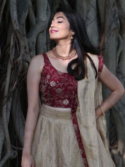 The natural outdoor lighting highlights the fresh, dewy finish of the makeup.