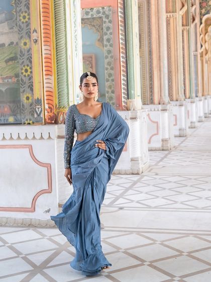 A full-length shot of our dusty blue pre-draped saree. We believe in our products and our service.