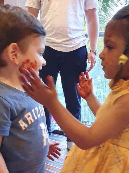 Playdates are all about making friends and having fun. Here, two children are playfully sharing some messy paint during a class.