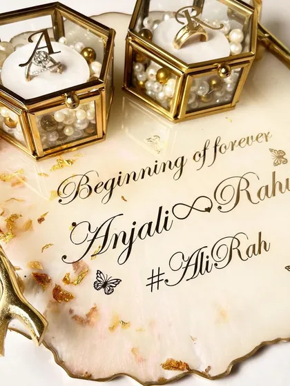 This elegant white resin tray is decorated with gold leaf flakes and butterfly accents. It features gold branch handles and is personalized with the couple's names and hashtag.