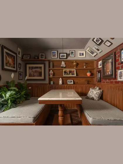 This cozy booth at Echoes is defined by raw brick, warm wood, and a ceiling filled with framed memories. The marble-topped table adds a touch of classic elegance to the rustic setting, perfect for conversations and comfort.