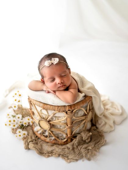 A simple, boho-inspired setup with a rattan stool and some daisies. The neutral colors keep the focus on the peacefully sleeping baby.