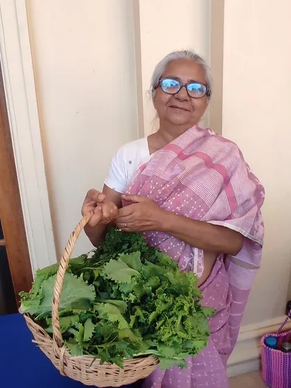 A customer holding a basket overflowing with fresh mustard greens.