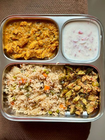 A flavorful meal of vegetable pulav with chicken curry, sautéed ivy gourd, and a side of raita.