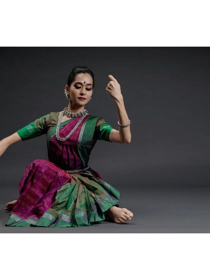 A seated pose from a studio photoshoot. The clean, controlled environment of a studio allows for a deep focus on the lines, posture, and expression of the dancer.