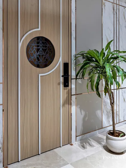 Sometimes simple is better. This modern entryway features a beautiful wood door with a geometric glass insert, complemented by a marble-paneled wall and a simple potted plant.