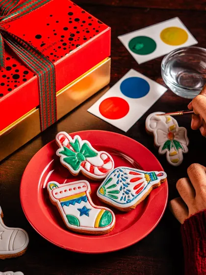 A finished set of 'Paint Your Own' Christmas cookies, showcasing the vibrant edible paints on stocking and candy cane designs. This is a wonderful and interactive gift for kids and adults alike.