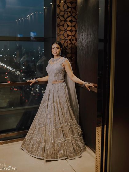 A bride posing against a window with a city view at night. The contrast between her traditional gown and the modern cityscape is stunning.