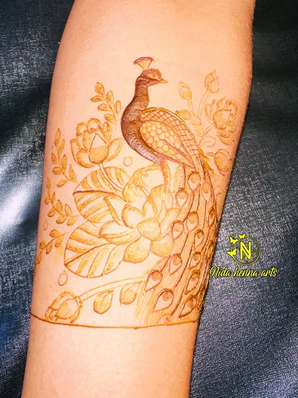 A close-up of the peacock and lotus design, showing the delicate line work. We practice these motifs on paper before applying them to the skin.