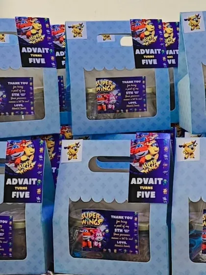 A still shot of the 'Super Wings' themed return gift boxes for Advait's fifth birthday party. Each box is filled with goodies and includes a custom thank you note.