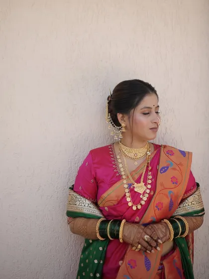 A serene portrait of the bride against a simple wall, letting her traditional attire and makeup shine.
