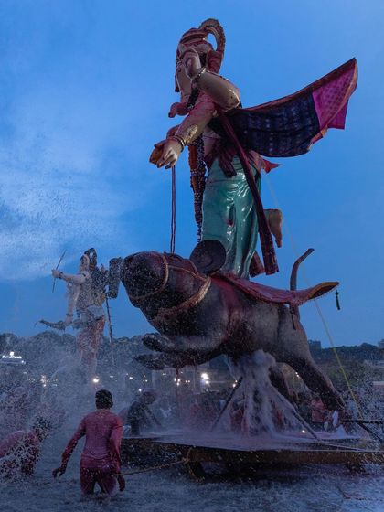 An unusual Ganesha idol riding a mouse is immersed in the water, showcasing the creative and varied iconography of the festival.